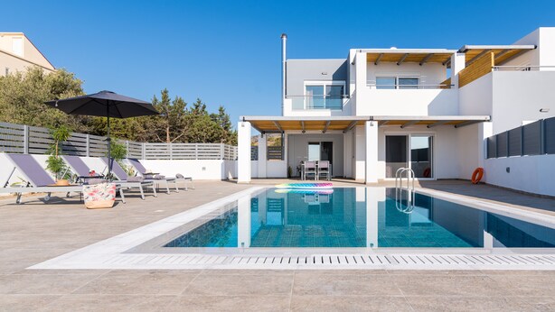 Et moderne poolområde med klart blåt vand, liggestole og en træpergola.