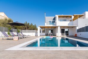 Un espace piscine extérieur moderne, doté d’une piscine à l’eau cristalline, de chaises longues et d’une pergola en bois.