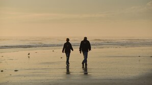 Two people walking on a beach with the ocean in the background. - Beautiful Condo steps away from Beach (St. Augustine Beach)