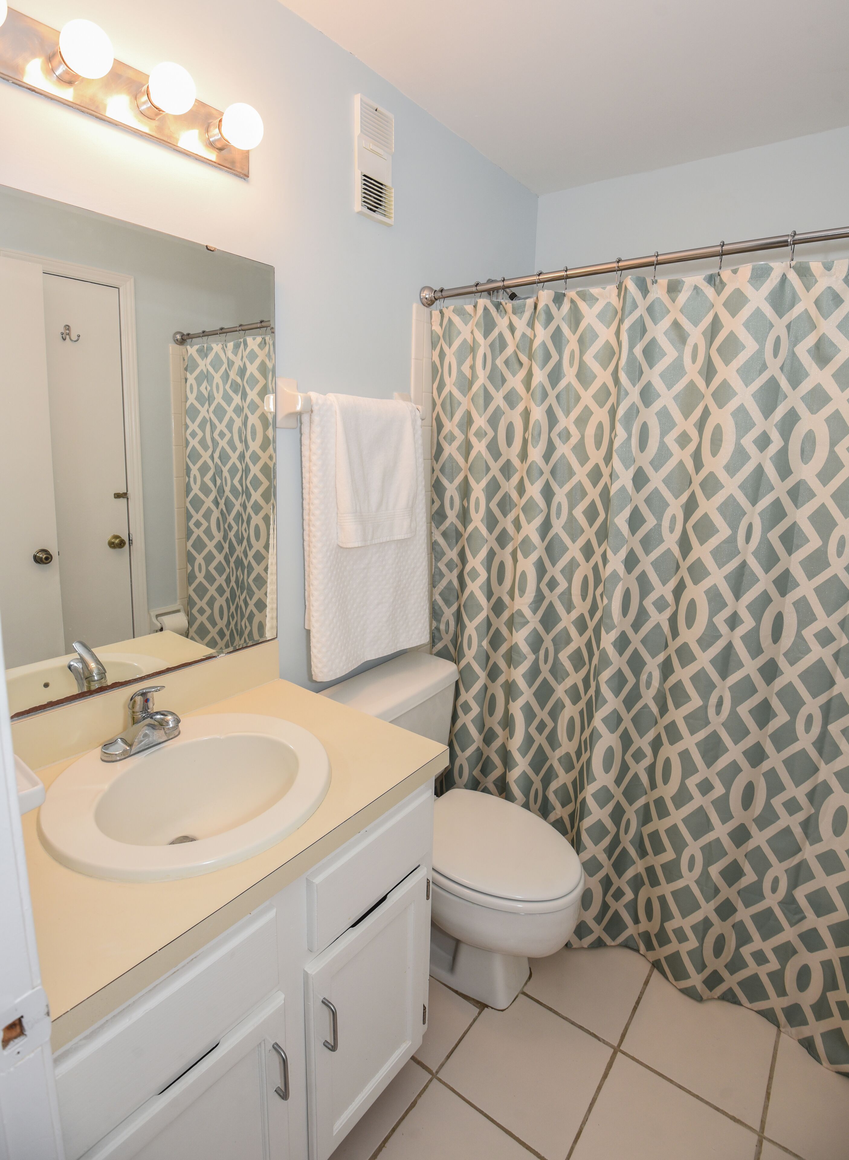 A bathroom with a sink, toilet, and shower curtain.