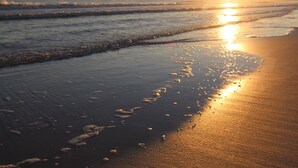 Una playa con olas y un atardecer.
