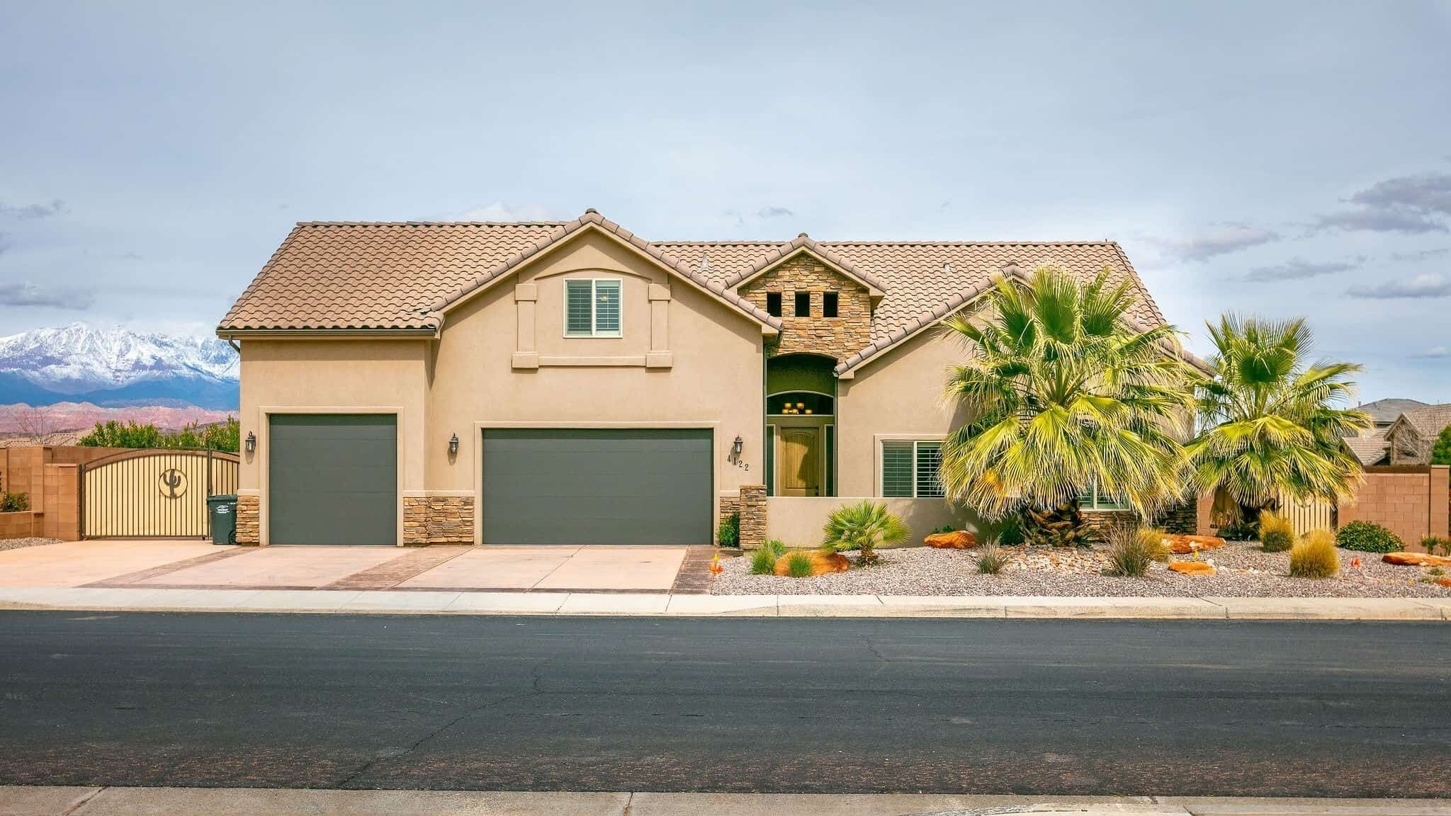 A two-story house with a garage, a front porch, and a palm tree in the front yard.