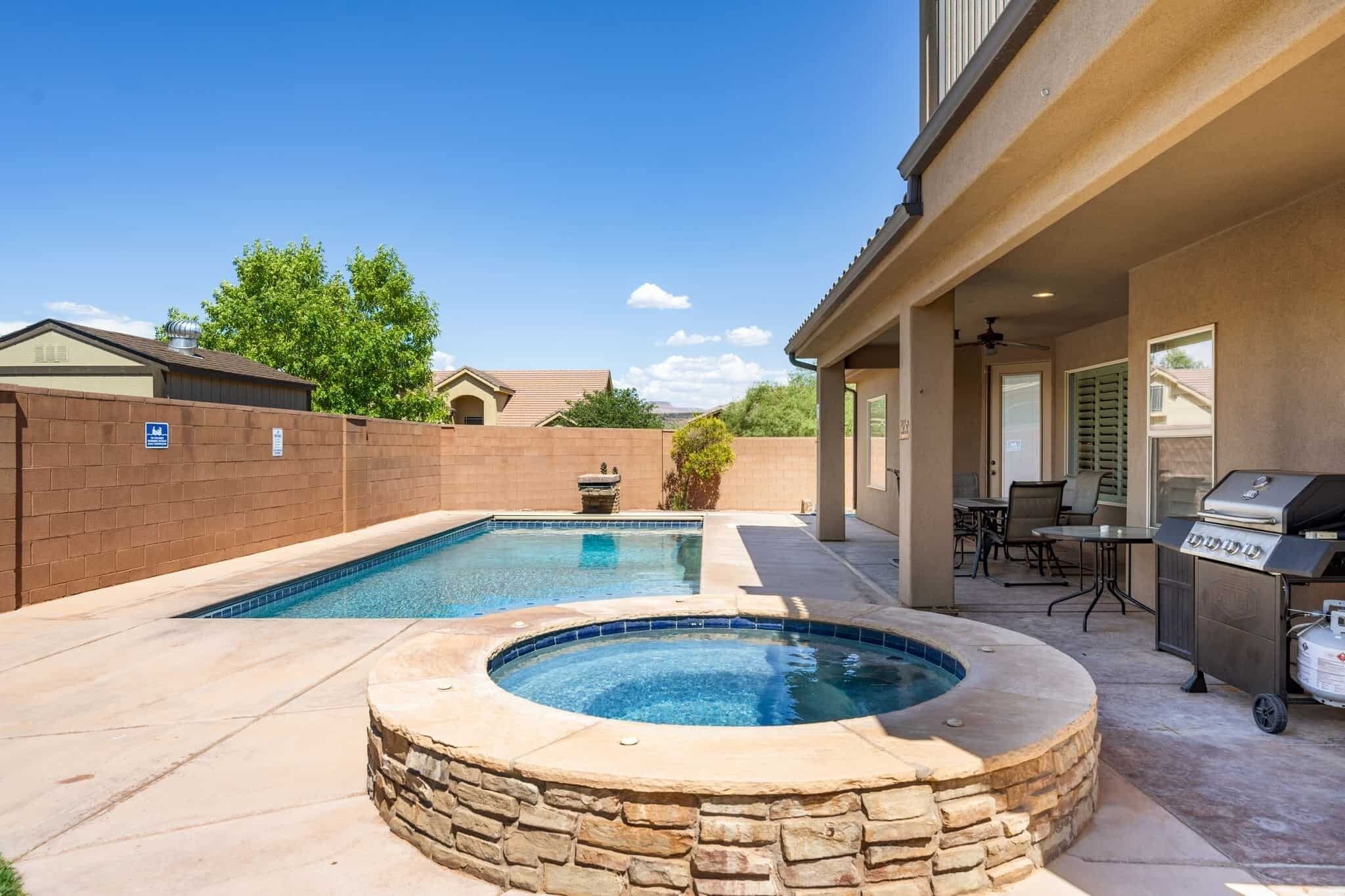 Un jardin avec une piscine rectangulaire, un jacuzzi et un barbecue.