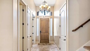 A hallway with a wooden door, a chandelier, and a staircase. - Escondido by RedAwning (Hurricane)