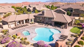 A residential area with a large swimming pool, multiple houses, and a mountain backdrop. - Views Over Coral Canyon by RedAwning (Washington)