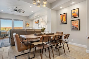 A dining area with a wooden table and chairs, a ceiling fan, and artwork on the walls. - Views Over Coral Canyon by RedAwning (Washington)