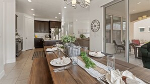 A modern kitchen with dark cabinets, a wooden dining table set for four, and a chandelier. - Fun in the Sun Retreat by RedAwning (Washington)