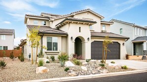 A two-story house with a tiled roof, a garage, and a landscaped front yard with rocks and plants. - Fun in the Sun Retreat by RedAwning (Washington)