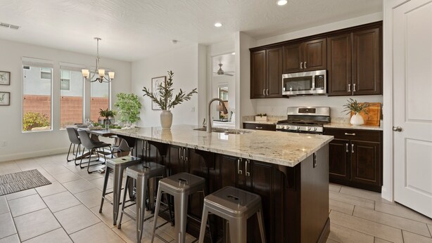 A modern kitchen with dark wood cabinets, stainless steel appliances, and a large island with bar stools. - Fun in the Sun Retreat by RedAwning (Washington)