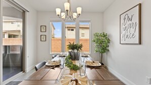 A dining room with a long wooden table set for six, a chandelier, and a 'Our happy place' sign on the wall. - Fun in the Sun Retreat by RedAwning (Washington)