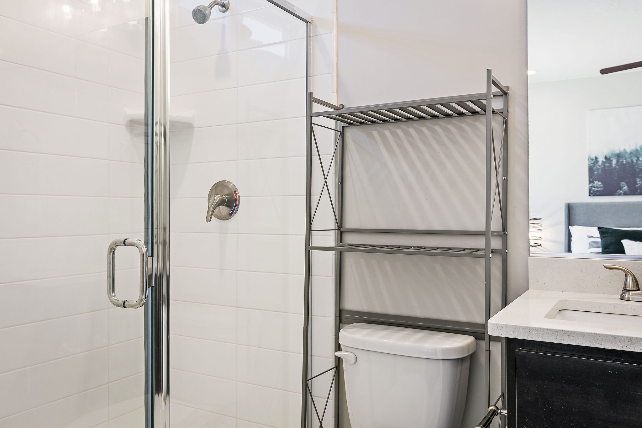 Un baño moderno con cabina de ducha de vidrio, inodoro blanco y toallero de metal.
