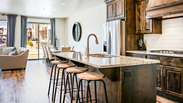 A modern kitchen with a large island, bar stools, and dark wooden cabinets. - Fun Times & Tan Lines by RedAwning (Washington)