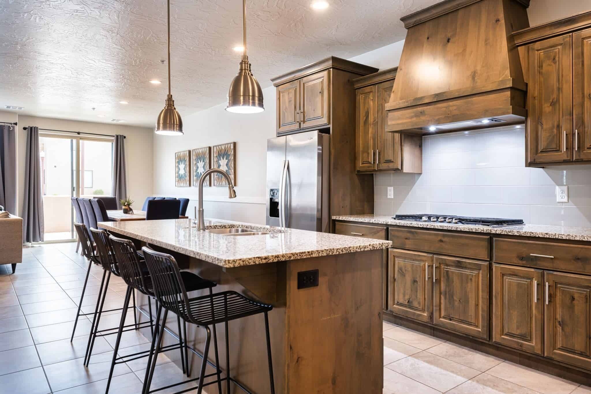 Una cocina moderna con armarios de madera, un refrigerador de acero inoxidable y una isla grande con taburetes de bar.