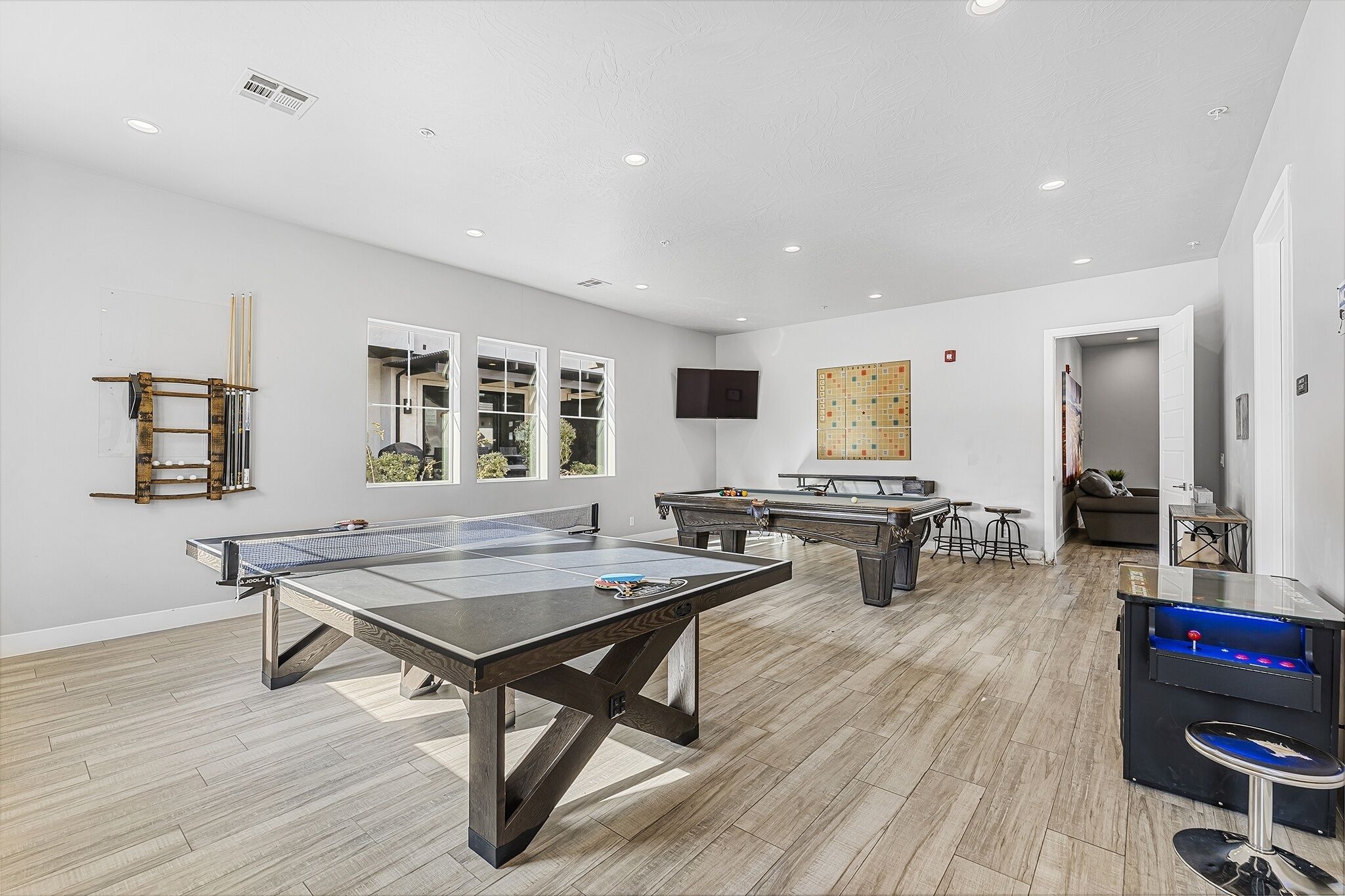 A spacious room with a ping pong table, two foosball tables, and a foosball table with a blue base.