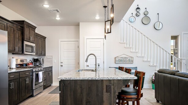Una cocina moderna con gabinetes de madera oscura, electrodomésticos de acero inoxidable y una isla de granito.