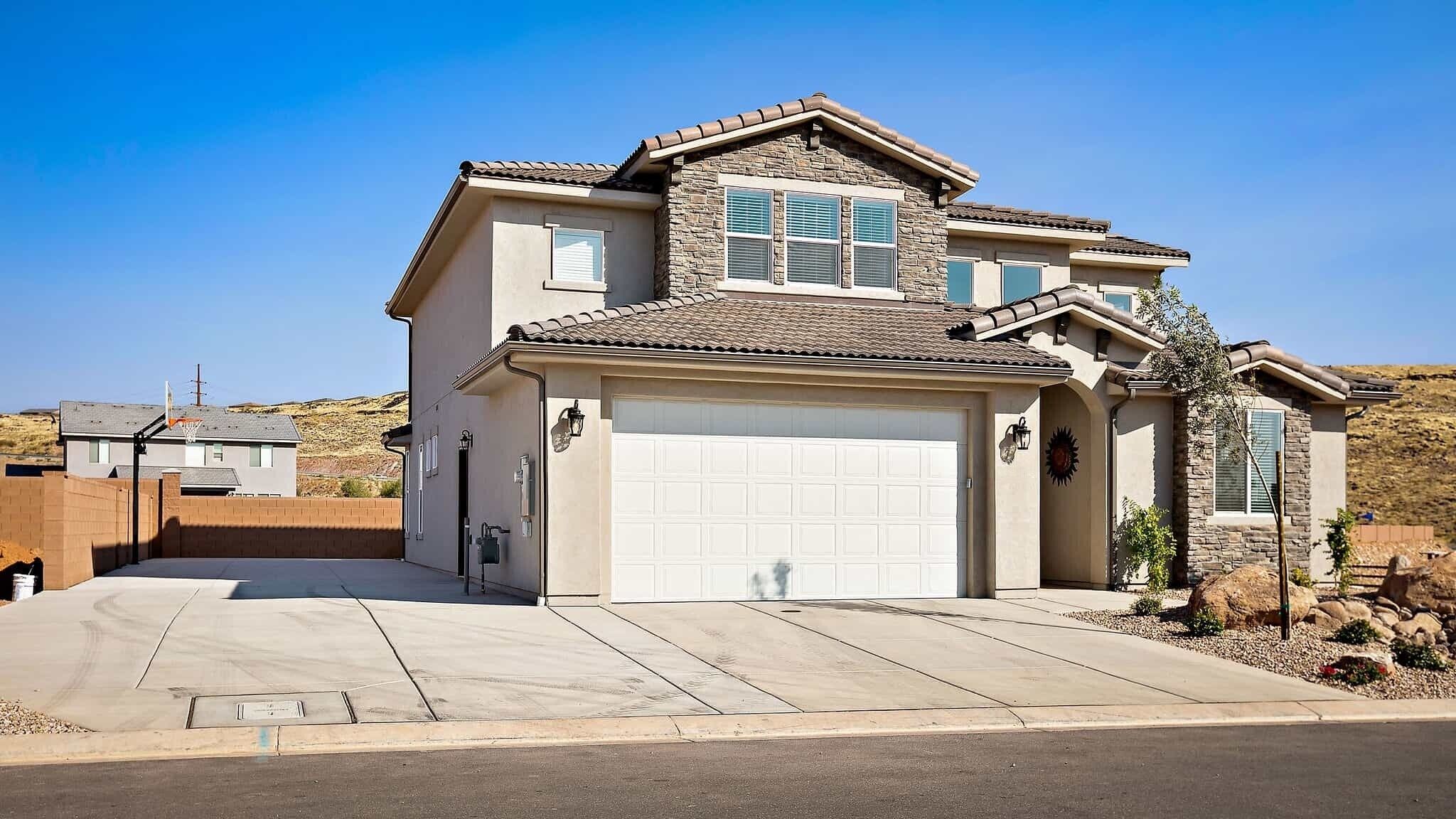 A two-story house with a garage, a basketball hoop, and a landscaped front yard.