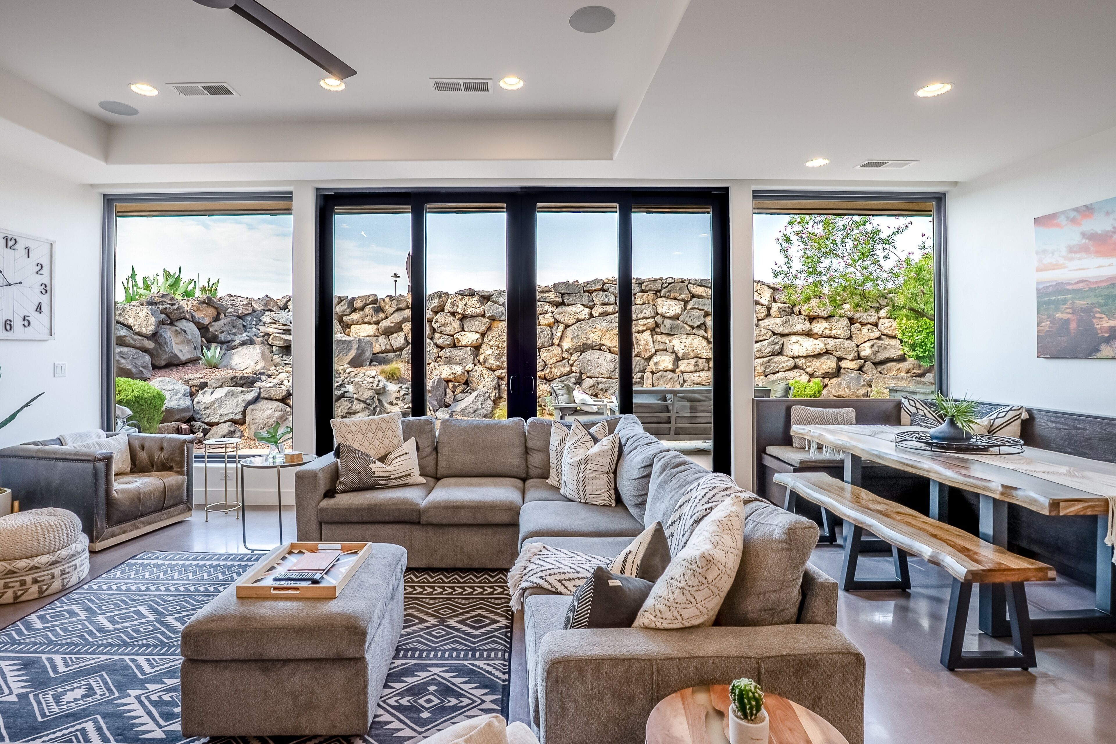 A spacious living room with a large sectional sofa, a coffee table, and a dining area with a bench.