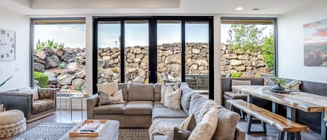 A spacious living room with a large sectional sofa, a coffee table, and a dining area with a bench.