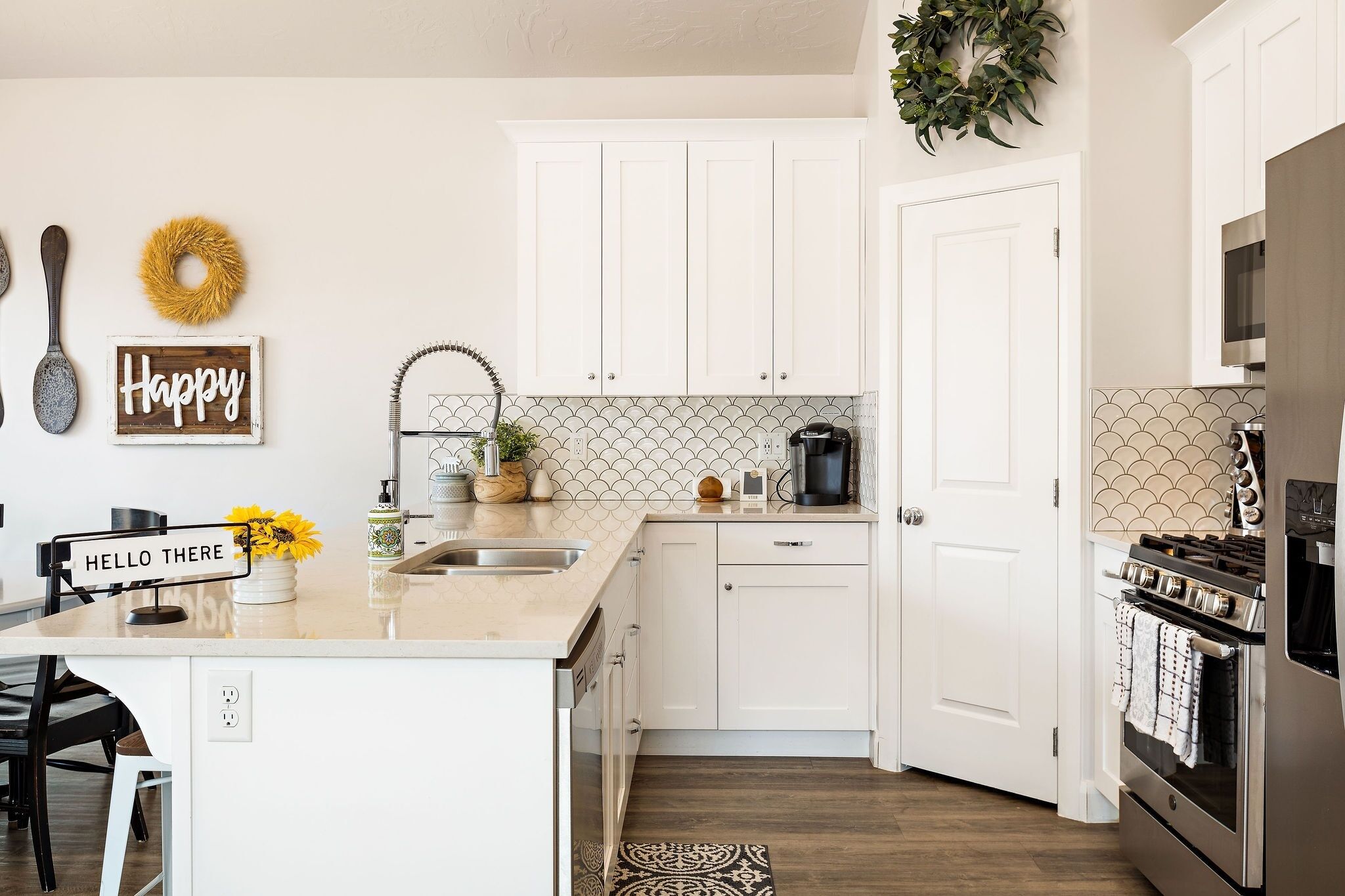 A modern kitchen with white cabinetry, a central island, a coffee maker, and a stainless steel stove.