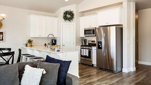 Una cocina moderna con gabinetes blancos, electrodomésticos de acero inoxidable y una isla central.
