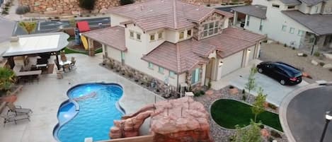 A residential property with a swimming pool, a covered patio, and a car parked in the driveway.