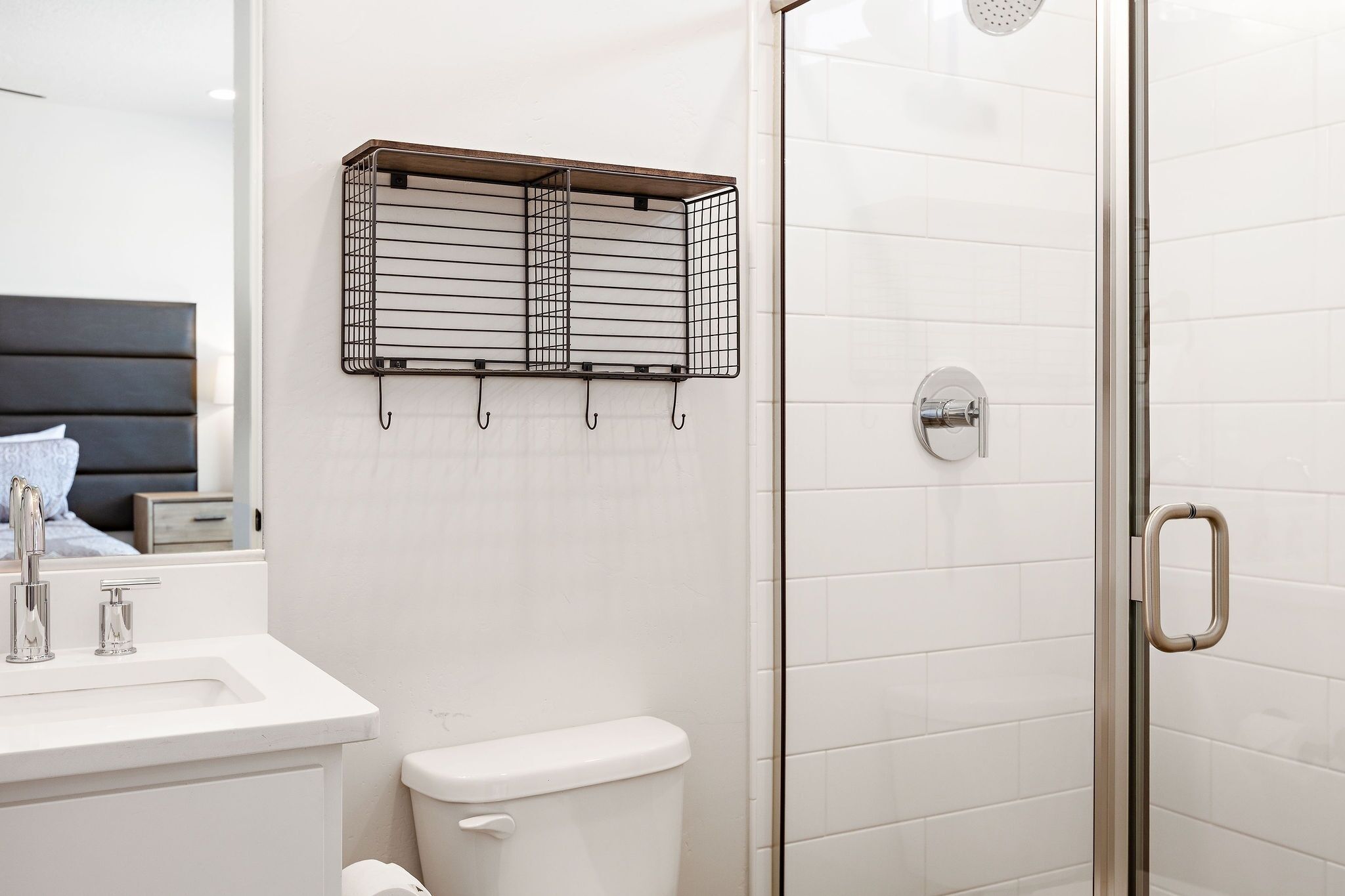 A modern bathroom with a white sink, toilet, and a glass shower enclosure.