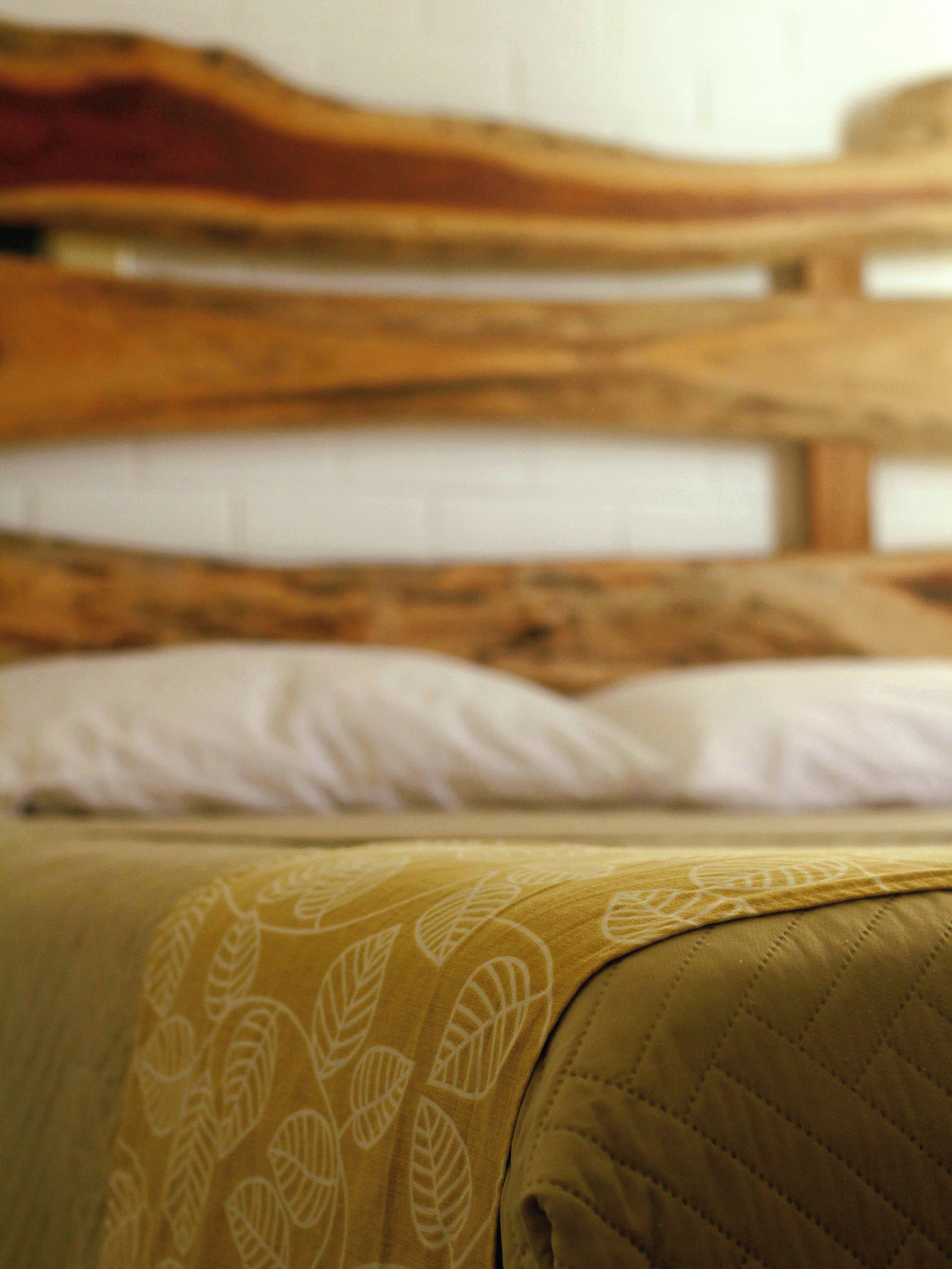 A bed with a wooden headboard and a patterned blanket.
