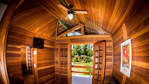 A wooden cabin with a ceiling fan, a TV, and a view of the outdoors. - Pousada Suarez (Itatiaia)