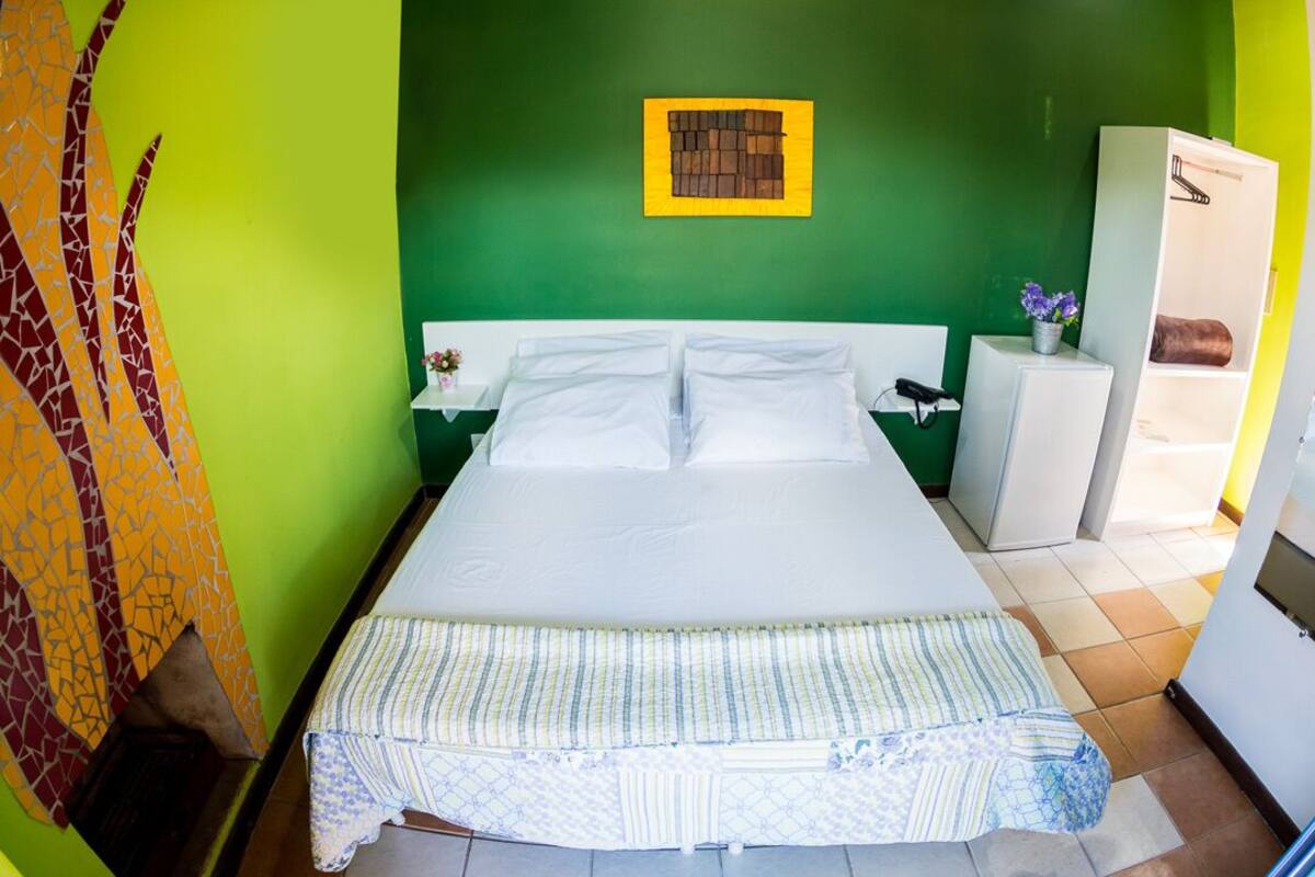 Una habitación con cama, mesita de noche, un pequeño armario y un adorno en la pared.