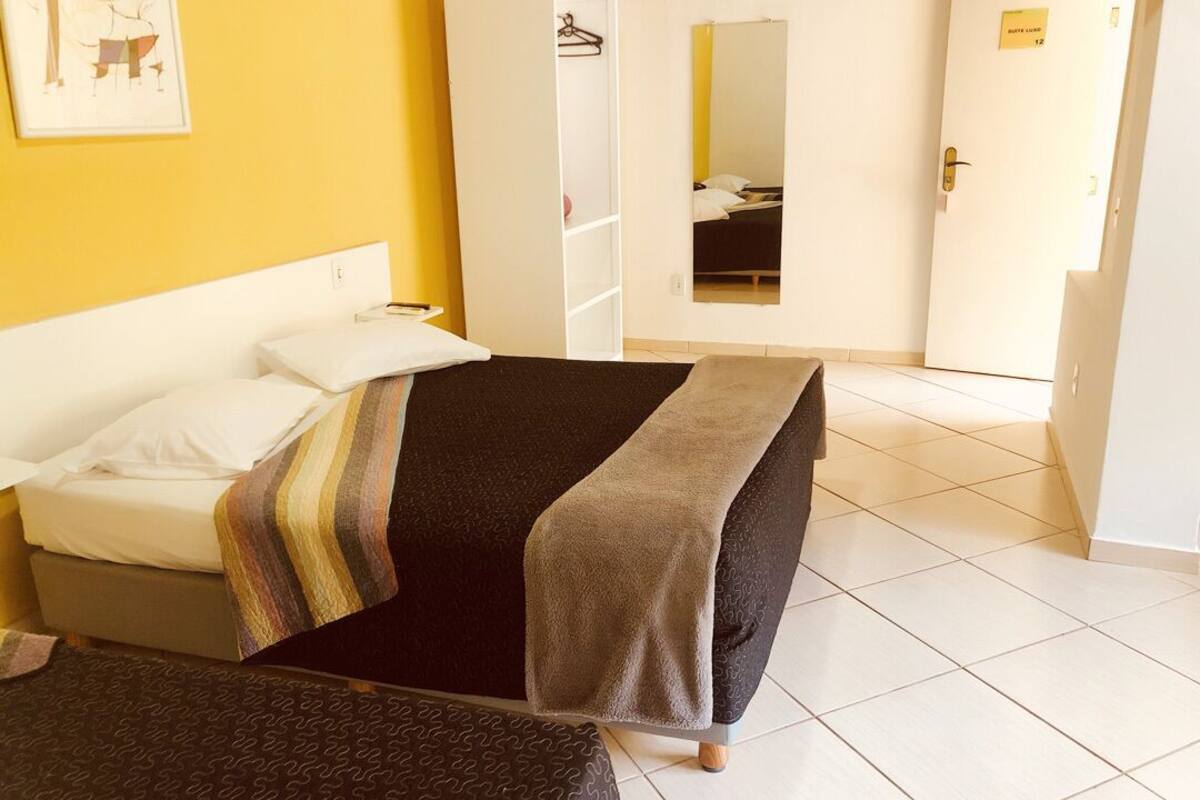 Una habitación de hotel con cama, armario, espejo y puerta.