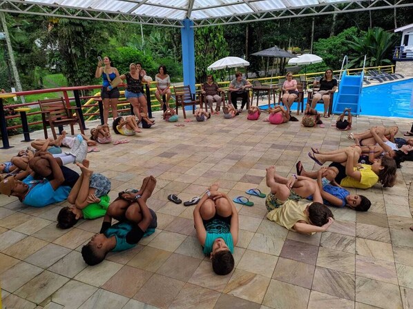 A group of people lying on the ground in a circle, possibly participating in an outdoor activity or exercise. - Pousada Suarez (Itatiaia)