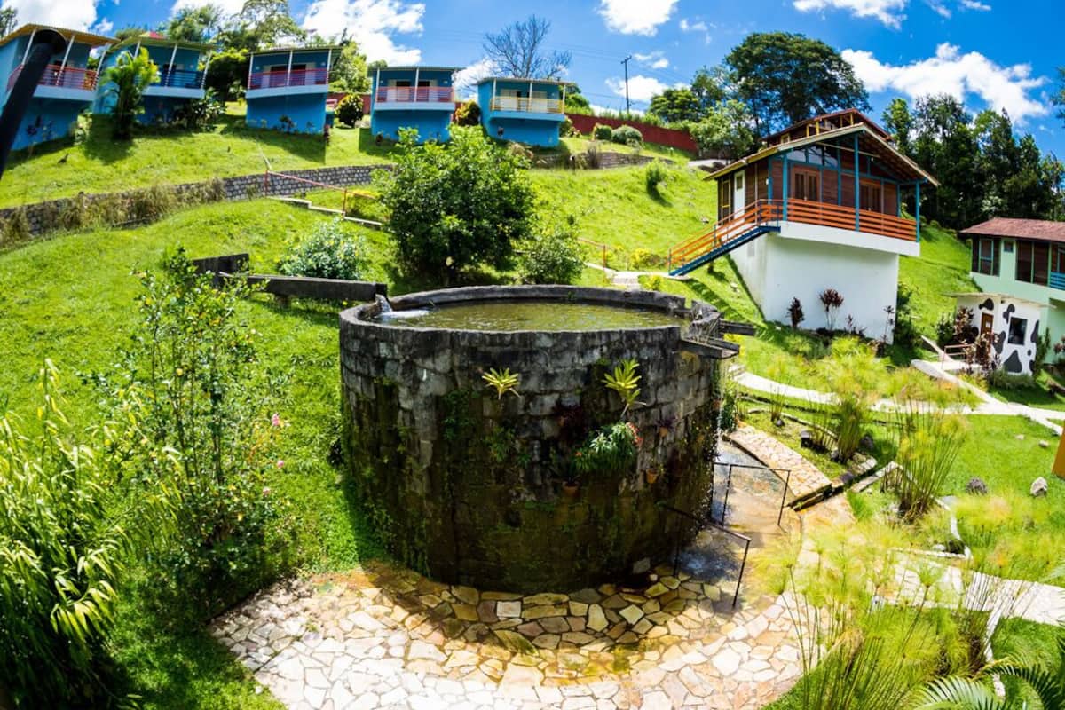 Una colina con varios edificios, incluyendo un depósito de agua grande y una escalera que lleva a un edificio con balcón.