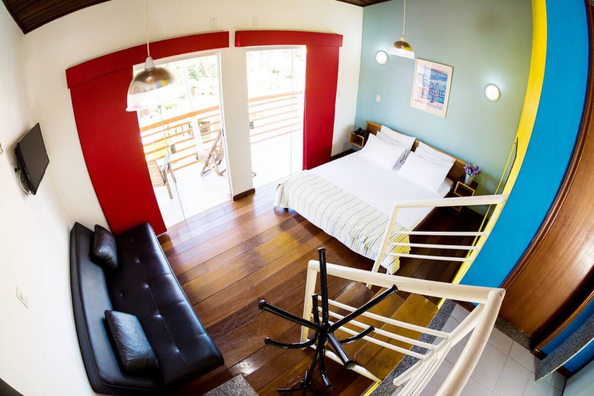 Un dormitorio con cama, sofá, sillón y escalera.