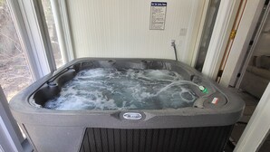 Un bain à remous doté d’un panneau de commande, d’un panneau d’avertissement et d’une marche permettant d’y accéder.