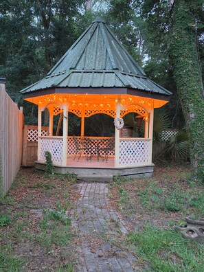 A gazebo with a conical roof and lattice railings, surrounded by a wooden fence and trees. - Minutes from the beach, with indoor hot tub (Daufuskie Island)