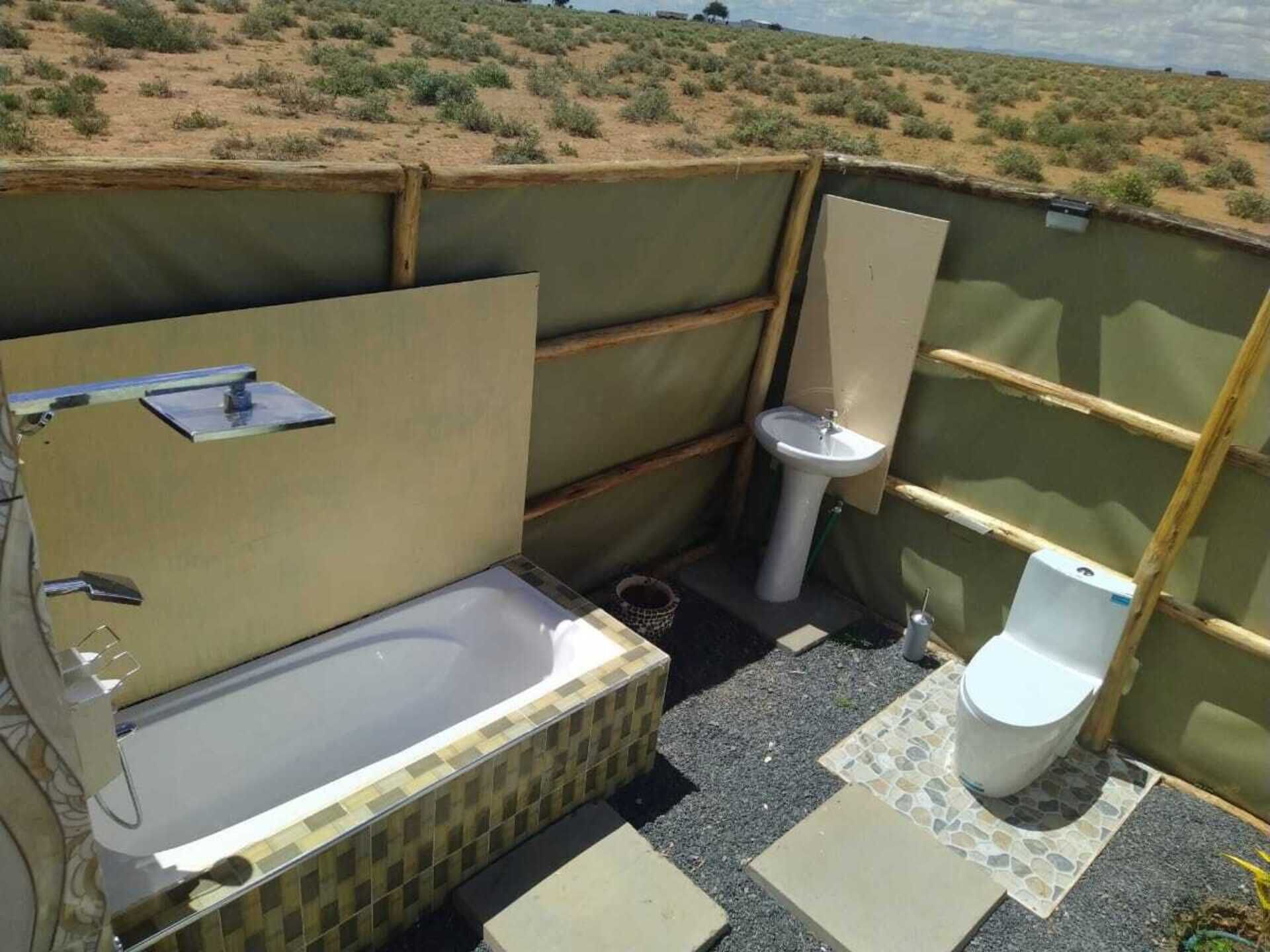 Un baño al aire libre pequeño y privado, con bañera, lavamanos e inodoro.