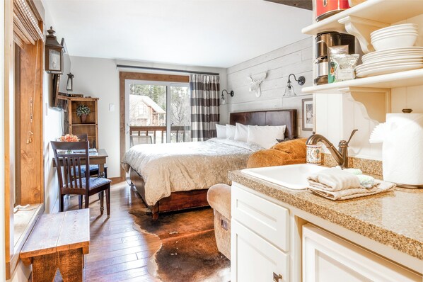 A cozy bedroom with a large bed, a wooden desk, and a dining table.