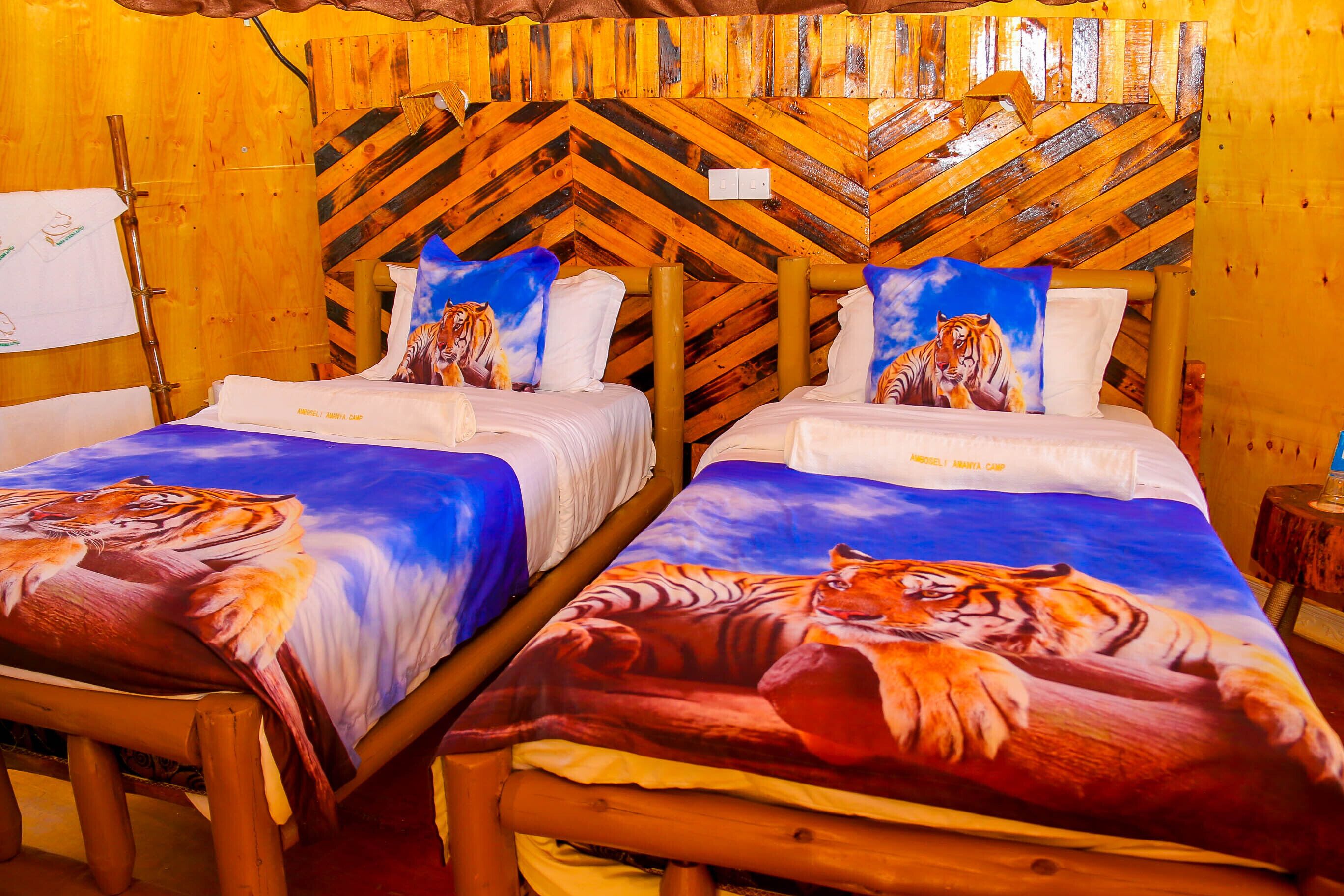 Two twin beds with tiger-themed bedding, wooden headboard with a chevron pattern, and a wooden floor.
