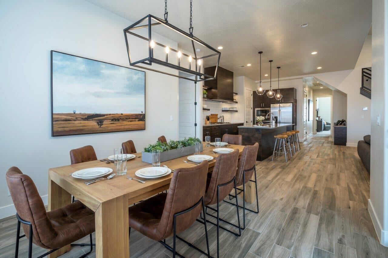 Un espace repas moderne avec une table en bois, des chaises marron et un luminaire suspendu.
