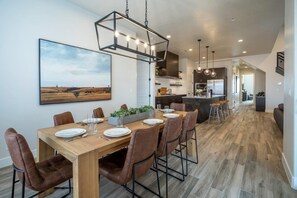 A modern dining area with a wooden table, brown chairs, and a hanging light fixture.