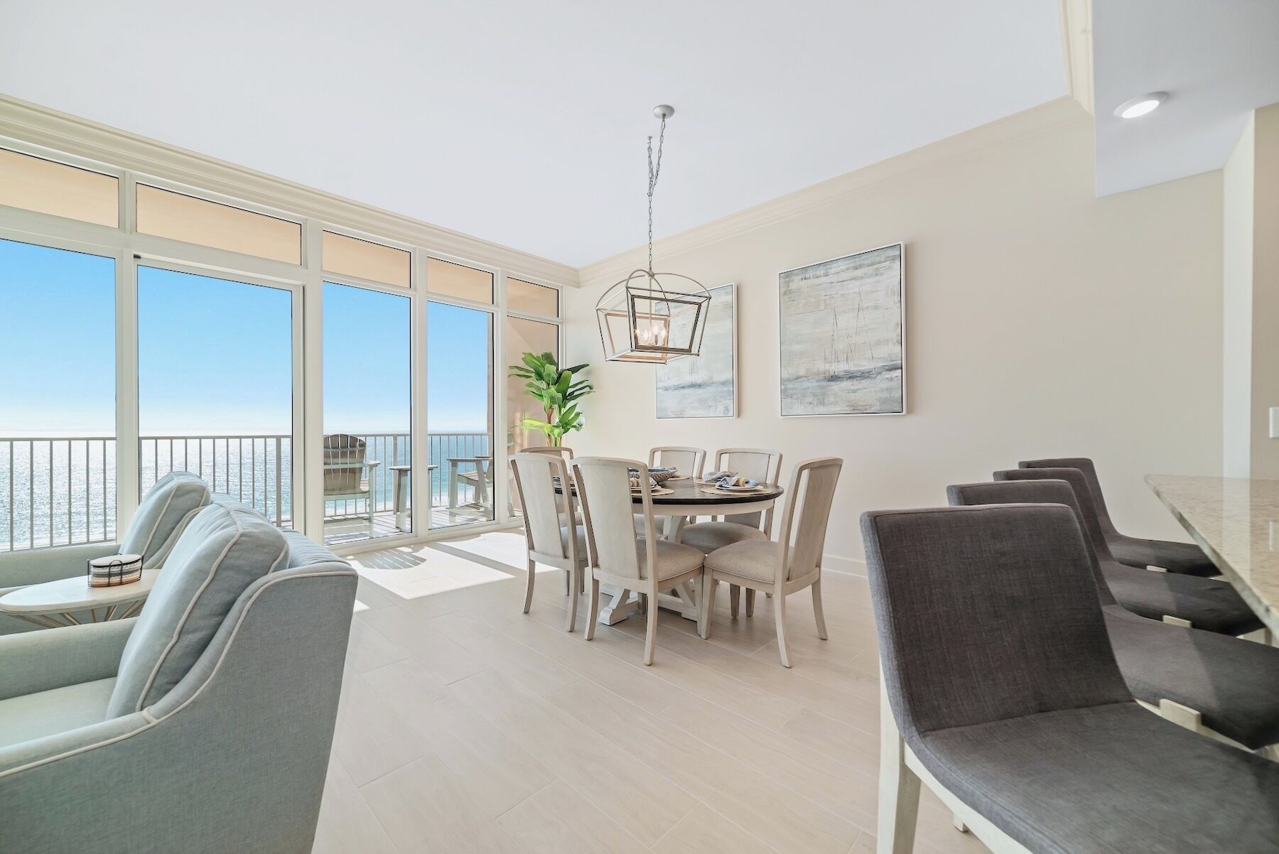 Un vaste espace dédié à la salle à manger offrant une vue sur la mer, un balcon et un lustre moderne.