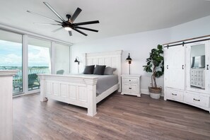 A bedroom with a bed, bedside tables, a ceiling fan, a potted plant, and a wardrobe.
