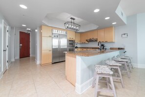 A modern kitchen with a central island, stainless steel appliances, and light wood cabinetry.