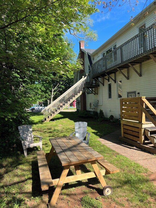 A wooden picnic table and chairs in a backyard with a house in the background.