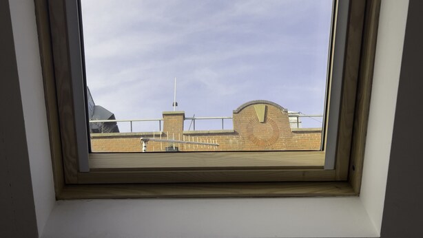 A skylight with a view of a brick building and a clear sky.