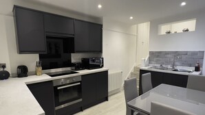 A modern kitchen with black cabinets, a white countertop, a built-in oven, a microwave, and a sink.