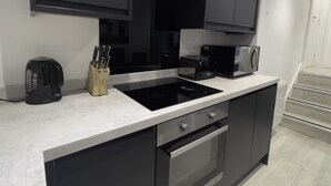 A modern kitchen with a built-in stove, microwave, and toaster. There is a knife block on the counter and a coffee maker.