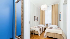 Habitación de hotel con dos camas, un espejo grande, piso de madera y vistas al exterior.