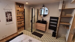 Une chambre à coucher avec un lit, un mur en bois, un miroir, un lavabo et une armoire.