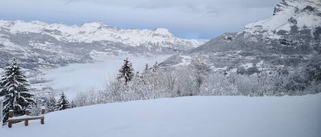 A snow-covered mountain landscape with a bench and trees.